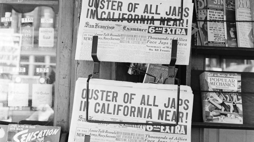 A black-and-white photograph of a newsstand from 1942 showing two copies of the San Francisco Examiner with a large headline reading "Ouster of All Japs in California Near!"