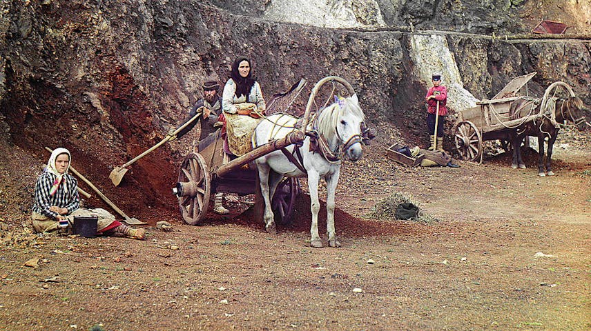A family of four, with shovels and horse-drawn wooden carts, working in an open-pit iron mine.