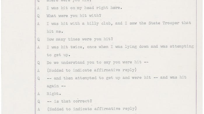 A scanned page (numbered 296) from an old typed legal document showing a question-and-answer interview, similar to a courtroom testimony. A person describes being knocked down and struck twice on the head with a billy club by a State Trooper during a chaotic scene where people were being pushed and knocked over. The person says they were not knocked unconscious and could identify the trooper from a photograph. The Q and A format shows a questioner (Q) asking follow-up questions and the witness (A) answering them.