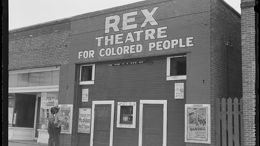 A brick theater with a sign that says Rex Theatre for Colored People on it.