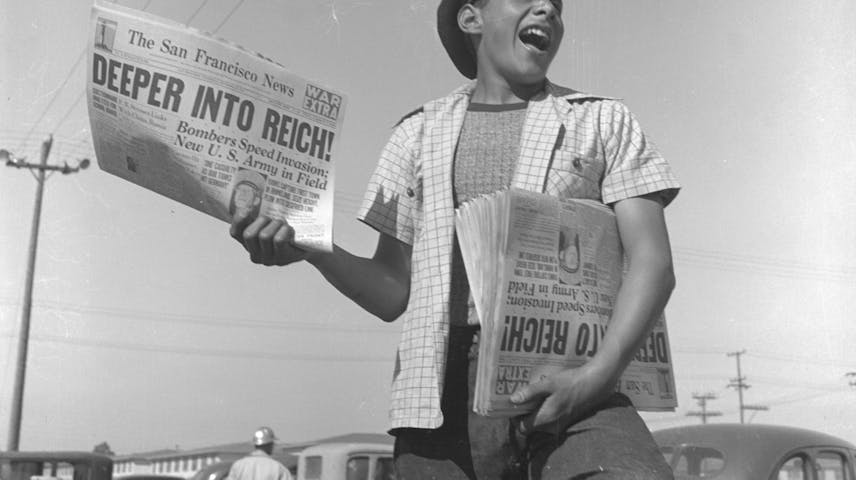 1944 image of a newsboy holding copies of the San Francisco News that read “Deeper into Reich!”